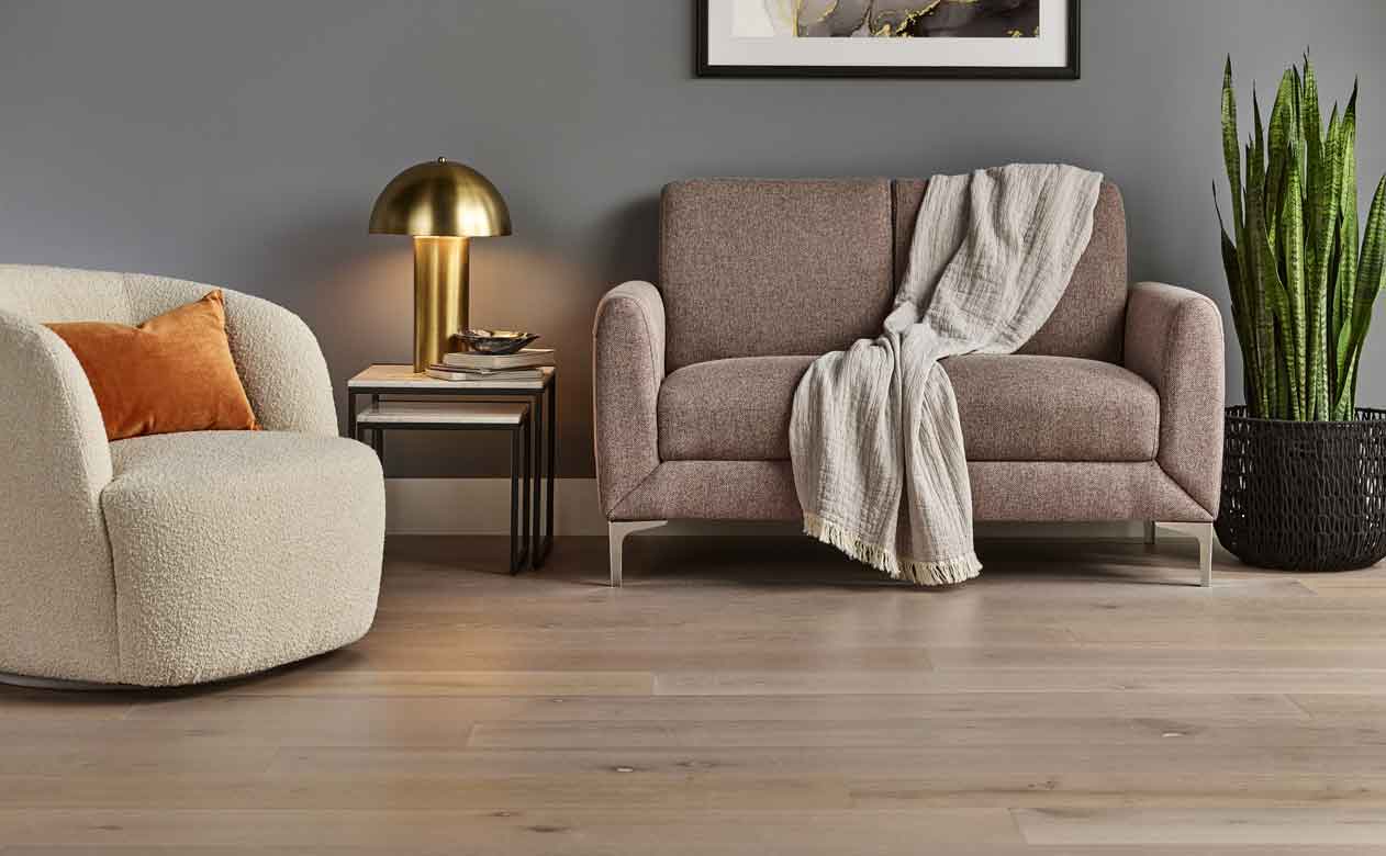 Hardwood flooring in a living room with brown love seat and cream accent chair